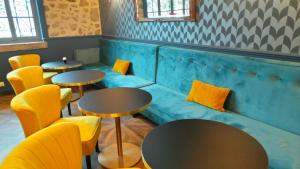 a room with tables and yellow chairs and a couch at Hotel Relais Du Postillon in Antibes