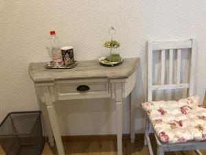 einen kleinen weißen Tisch mit einer Flasche und einem Stuhl in der Unterkunft Gast und Hof Spittel in Langenbruck
