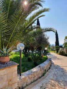a garden with palm trees and a stone wall at Casale Rocca Russa B&B in Villaggio Mosè