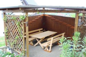 a wooden table and bench under a wooden pergola at Ferienwohnungen Dippold in Scheßlitz +27 photos