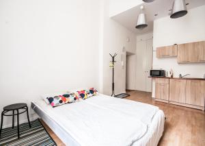 a white bedroom with a bed and a kitchen at Apartment in the center of Warsaw in Warsaw