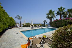 a swimming pool with chairs and a table next to it at Ayios Elias Pearl in Protaras