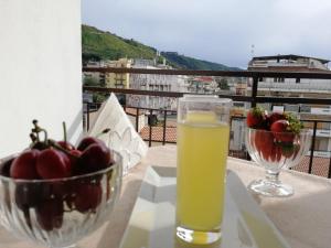 a glass of juice on a table with a bowl of fruit at OLYMPUS ROOM in Tropea