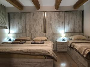 two beds in a bedroom with wooden walls at Le Petit in Tbilisi City