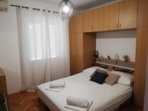 a bedroom with a large white bed with wooden cabinets at Guesthouse Radić in Dubrovnik