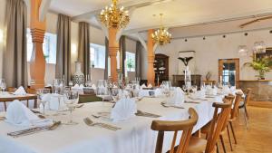 un comedor con mesas y sillas blancas y lámparas de araña en Gasthof zum Ochsen en Hammelbach