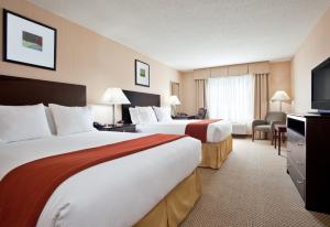 a hotel room with two beds and a flat screen tv at Holiday Inn Express Hotel & Suites Tipp City by IHG in Tipp City