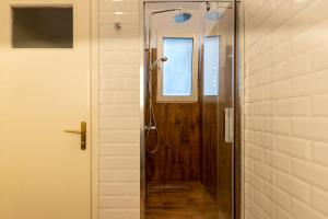 a shower with a wooden door and a window at Urban Senses Apt #2, a KalamataStay Property in Kalamata