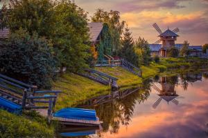 a river with a windmill and boats on it at HOT SPRINGS in Suzdal
