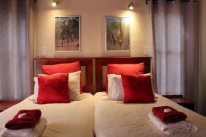 a bedroom with a large bed with red pillows at Woodpecker Lodge B&B in Hoedspruit