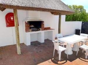 a patio with a fireplace and a table and chairs at Arniston Seaside Cottages in Arniston