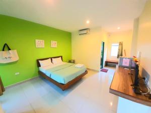 - une chambre avec un lit et un mur vert dans l'établissement The Moonlight Resort, à Ban Chang