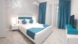 a bedroom with a large white bed with blue accents at Villa George in Constanţa