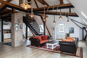 a living room with two leather chairs and a staircase at The Bricks 1903 Lofts - Central Bistrita in Bistriţa