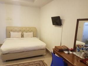a bedroom with a bed and a desk and a television at Mina Homestay Syariah in Bukittinggi