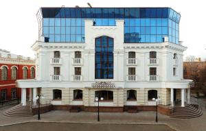 Hotel Aristokrat في بولتافا: مبنى ابيض كبير مع مبنى زجاجي