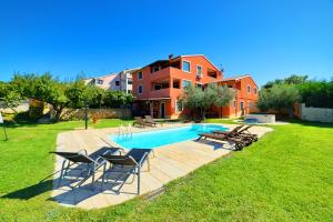 a swimming pool with chairs and a house at Apartment Villa Mare2 with pool, sea view and hydromassage in Banjole