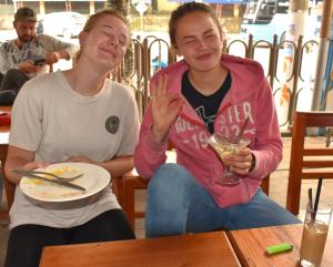 河江的住宿－LiLa Inn & Motorbike Tours Ha Giang，坐在餐桌上吃一盘食物的男人和女人