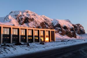 a building in the snow with a mountain in the background at Hótel Kría in Vík