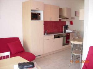 a living room with a red couch and a kitchen at Lac de Eau d Heure Appartement C1 Famille RANOCHA DUPREZ in Badon