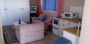 a kitchen with a living room with a couch and a microwave at Gansbaai Lodge & Backpackers in Gansbaai