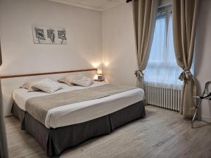 een slaapkamer met een groot bed en een raam bij Les Camelias in Bagnoles de l'Orne