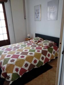 ein Bett mit einer Decke in einem Schlafzimmer in der Unterkunft Passionné de la plage in Dunkerque