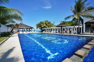 a swimming pool with palm trees and a building at Club Hari Dive Resort in Moalboal