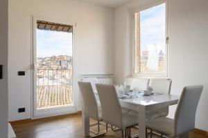 een witte eetkamer met een tafel, stoelen en ramen bij Appartamento panoramico San Martino 12 in Siena