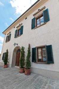 a building with green shuttered windows and potted plants at VillAmorosa in Calci
