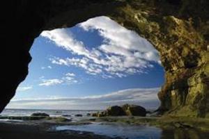 a stone archway in a rock formation at the beach at Apartamento Confortable Samai Huasi in Las Grutas