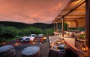 a patio with a table and chairs and a fireplace at Kwandwe Melton Manor in Grahamstown