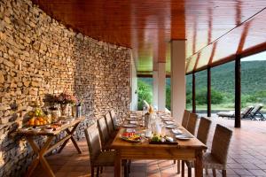 a dining room with tables and chairs and a stone wall at Kwandwe Melton Manor in Grahamstown