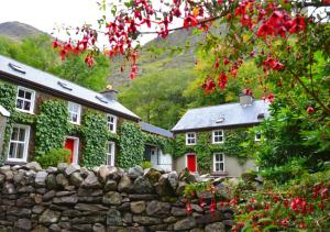 a stone fence in front of a house with red doors at Delphi Lodge in Leenaun