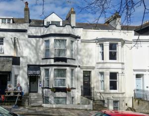 a white house with people sitting outside of it at The George Guest House in Plymouth