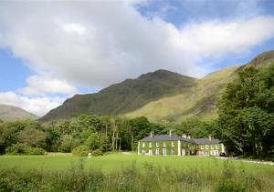 a house in a field with mountains in the background at Delphi Lodge in Leenaun