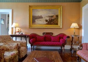 a living room with a red couch and a painting at Delphi Lodge in Leenaun