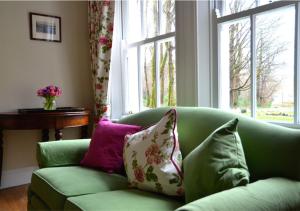 a green couch with pillows in a living room with a window at Delphi Lodge in Leenaun