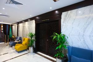 a lobby with a yellow chair and blue chairs at Bait Aldiyafah Hotel Apartments in Jeddah