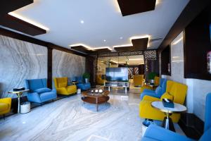 a lobby with blue and yellow chairs and a television at Bait Aldiyafah Hotel Apartments in Jeddah