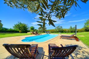 a swimming pool with two chairs and a table and a tree at Apartment Villa Mare3 with pool, sea view and hydromassage in Banjole