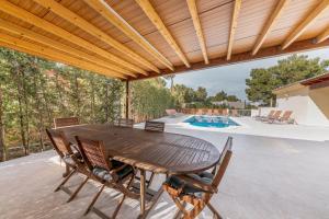einen Holztisch und Stühle auf einer Terrasse mit einem Pool in der Unterkunft YupiHome Villa Bahía de Palma - Family Only in Cala Vinyes