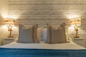 a bedroom with a bed with two lamps on tables at No33 BRACKEN BOUTIQUE COTTAGE in Brancaster +3 photos