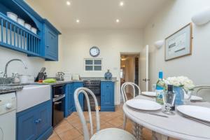 a kitchen with blue cabinets and a table with chairs at No33 BRACKEN BOUTIQUE COTTAGE in Brancaster