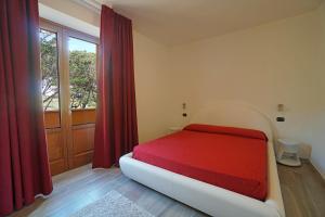 1 dormitorio con cama roja y ventana en Cascina al Colle, en Populonia