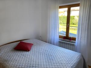 Bett mit rotem Kissen in einem Zimmer mit Fenster in der Unterkunft Sea View Istrian Countryside Apartment - ROTA in Dragonja
