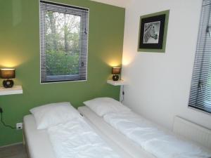 uma cama num quarto com paredes verdes e duas janelas em Rekerlanden 273 em Schoorldam