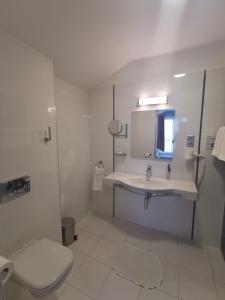 a white bathroom with a sink and a toilet at Gokart Hotel in Kecskemét