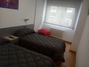 um quarto com 2 camas e uma janela em Hostal Outarelo em Ourense