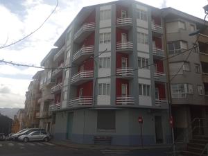 um edifício de apartamentos alto com varandas vermelhas e brancas em Hostal Outarelo em Ourense